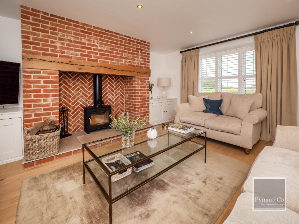 Cottage extension — living room interior with brick fireplace, oak beam and log burner