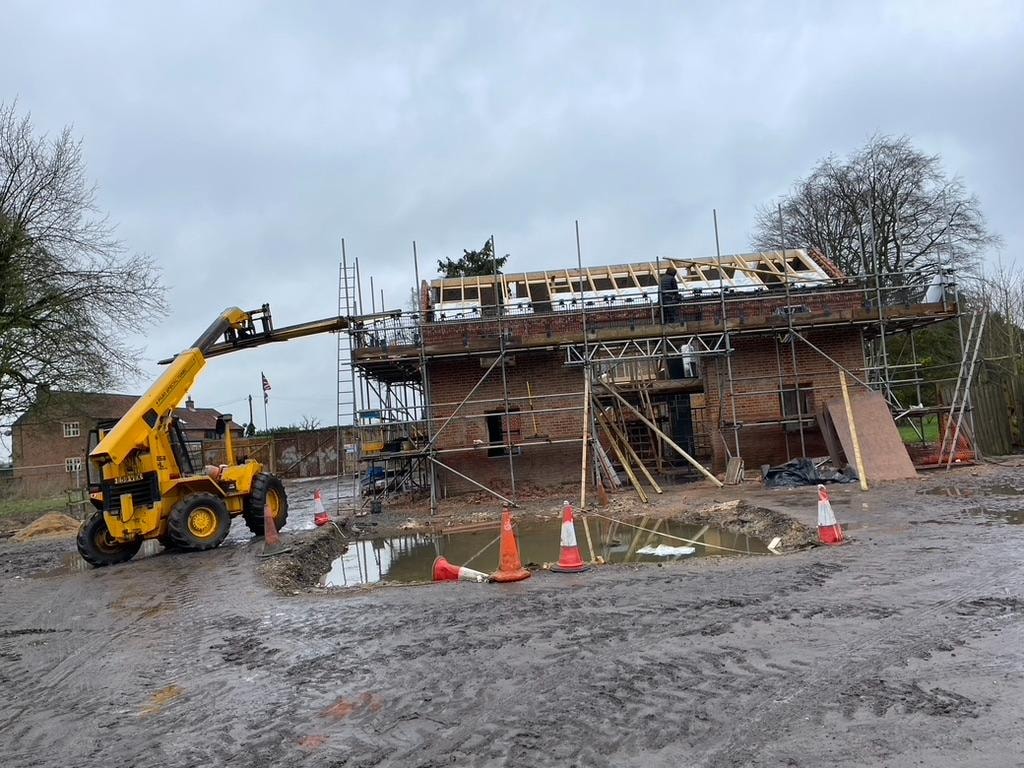The Grain Barn — roof structure under construction with telehandler on site