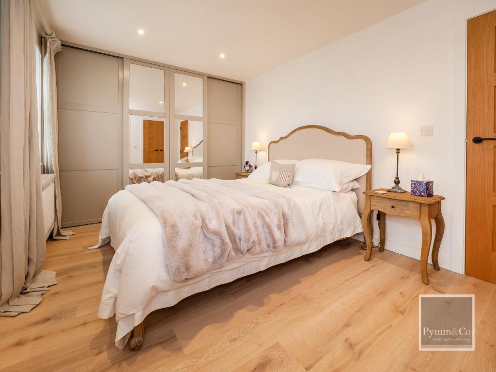 Malthouse refurbishment — master bedroom with oak flooring, fitted wardrobes and French-style bed