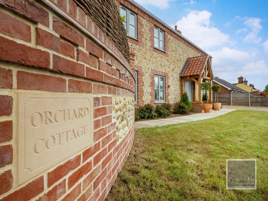 Orchard Cottage — brick and flint exterior with oak porch and stone name plaque